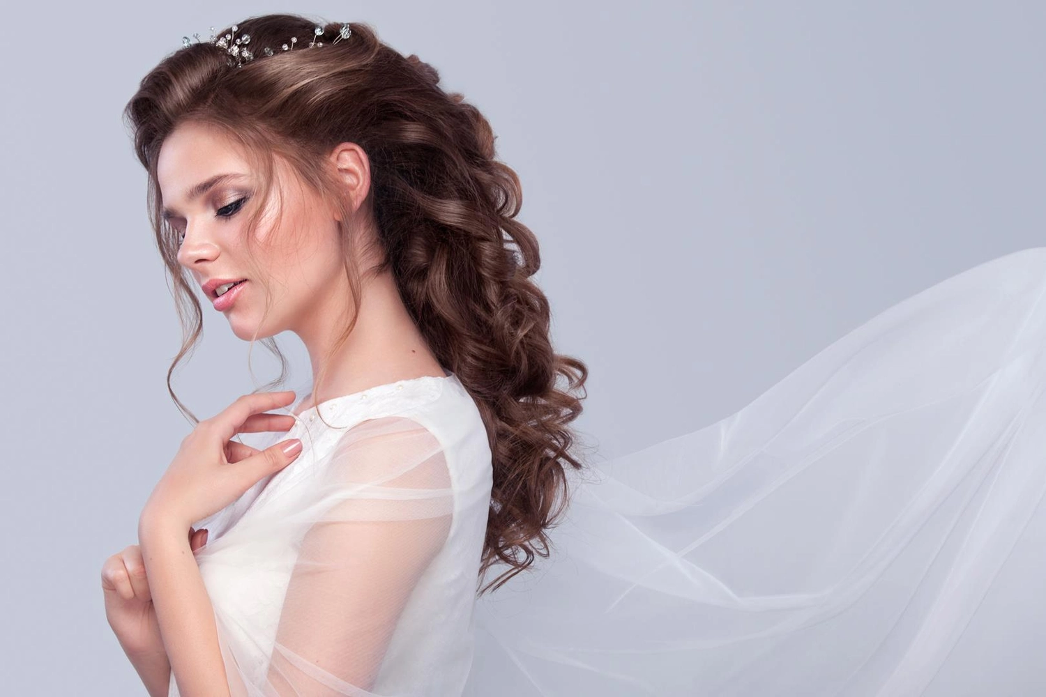 Wunderschöne Braut mit modischer Hochzeitsfrisur – vor grauem Hintergrund. Nahaufnahme einer jungen, bezaubernden Braut. Hochzeit. Studioaufnahme mit Platz für Text.