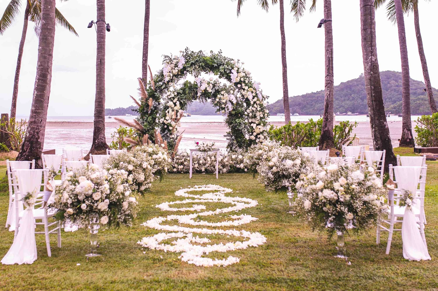 Hochzeitszeremonie. Mit Blumen geschmückter Bogen auf dem Rasen, Strand im Hintergrund, Meer im Sommer.